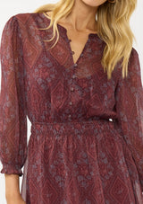 [Color: Wine/Rose] A detail image of a blonde model wearing a floral diamond print chiffon mini dress with metallic thread details, 3/4 sleeves, a button front, and an elastic waist. A special occasion dress for weddings and holidays. 