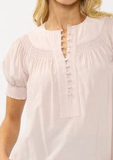 [Color: Rosewater] A detail image of a blonde model wearing a light pink puff sleeve top with smocked cuffs and button front. A sweet and soft pink top for the office and casual outings. 