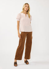 [Color: Rosewater] A front facing image of a blonde model wearing a light pink puff sleeve top with smocked cuffs and button front. A sweet and soft pink top for the office and casual outings. 