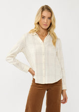 [Color: Natural/Silver] A front facing image of a blonde model wearing an off white windowpane shirt with metallic thread details. Featuring a collared neckline, button front, and button button cuff closure. A western influence shirt for the fall season. 