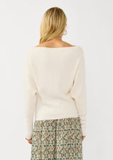 [Color: Natural] A back facing image of a blonde model wearing an off white waffle knit pullover sweater. With long sleeves, a relaxed fit, and a wide neckline that can be worn off the shoulder.