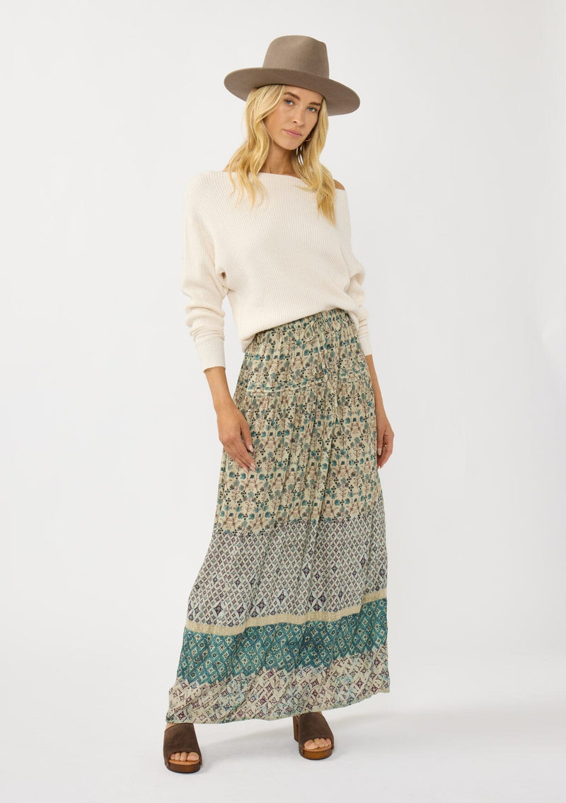 [Color: Taupe/Dusty Teal] A front facing image of a blonde model wearing a green teal floral bohemian skirt with an elastic drawstring waist and lace detail. A classic bohemian skirt for the fall season. 