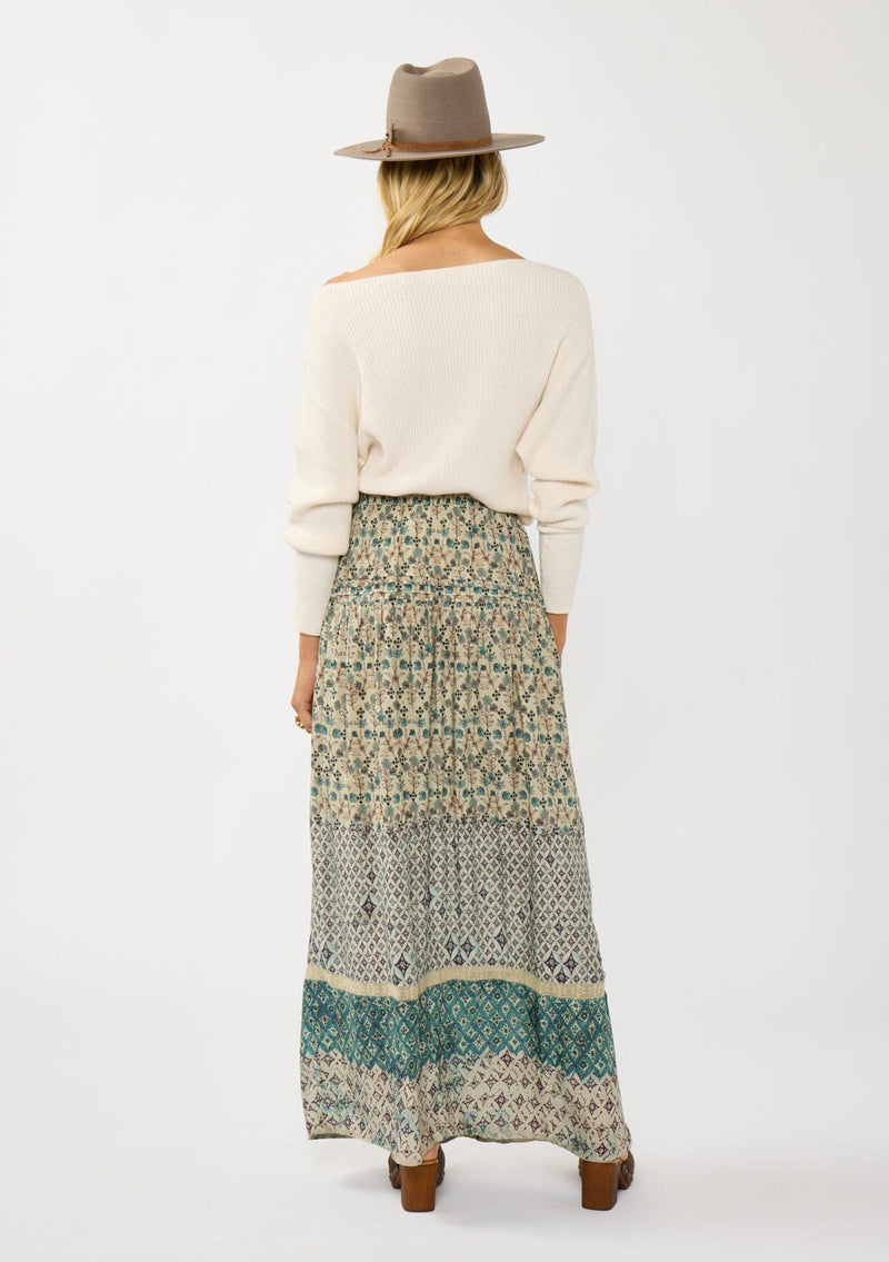 [Color: Taupe/Dusty Teal] A back facing image of a blonde model wearing a green teal floral bohemian skirt with an elastic drawstring waist and lace detail. A classic bohemian skirt for the fall season. 