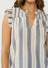 [Color: Blue/White] A detail image of a brunette model wearing a blue cotton striped top with a smoked yoke, a split v-neckline, and ruffled cap sleeves. 