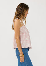 [Color: Vanilla/Rose] A side facing image of a brunette model wearing a pink floral print tank top with tie shoulder straps and a ruffled elastic neckline. A pretty spring tank top for casual outfits.