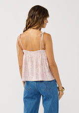 [Color: Vanilla/Rose] A back facing image of a brunette model wearing a pink floral print tank top with tie shoulder straps and a ruffled elastic neckline. A pretty spring tank top for casual outfits.