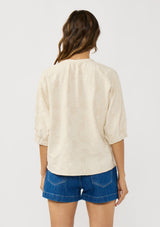 [Color: Natural] A back facing image of a brunette model wearing a beige linen-blend top featuring jacquard detailing, a button-front closure, and elbow-length sleeves with elasticized cuffs.