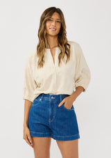 [Color: Natural] A front facing image of a brunette model wearing a beige linen-blend top featuring jacquard detailing, a button-front closure, and elbow-length sleeves with elasticized cuffs.