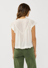 [Color: White] A back facing image of a brunette model wearing a flowy white bohemian top with short sleeves, a v-neckline, raw trim edges, and a shirred yoke. 