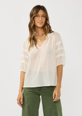 [Color: Ivory] A front facing image of a brunette model wearing an ivory sheer top with a split v-neckline and elbow length sleeves with pleats. A casual warm weather top for resort season. 