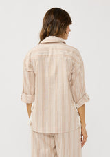 [Color: Sand/White] A back facing image of a brunette model wearing a striped shirt with a collared neckline, button front, roll tab sleeves, and a playful side tie detail. 