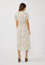 [Color: Natural/Dusty Peach] A back facing image of a brunette model wearing a dotted floral chiffon midi dress with clipped lurex for a touch of sparkle. Featuring a flattering v-neckline, short flutter sleeves, and an elastic waist at the back. 