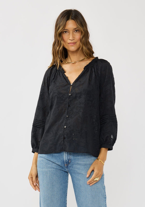 [Color: Black] A front facing image of a brunette model wearing a black floral jacquard blouse crafted in a lightweight cotton blend. Featuring a chic button front, 3/4 length sleeve, and pintuck details. 