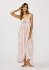 [Color: Vanilla/Rose] A front facing image of a brunette model wearing a pink floral bohemian maxi dress with a flowy tiered silhouette, crochet adjustable straps, a ruched bust detail, and ruffle trim accents. A pretty beach dress for vacation. 