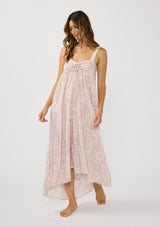 [Color: Vanilla/Rose] A front facing image of a brunette model wearing a pink floral bohemian maxi dress with a flowy tiered silhouette, crochet adjustable straps, a ruched bust detail, and ruffle trim accents. A pretty beach dress for vacation. 
