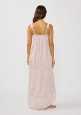 [Color: Vanilla/Rose] A back facing image of a brunette model wearing a pink floral bohemian maxi dress with a flowy tiered silhouette, crochet adjustable straps, a ruched bust detail, and ruffle trim accents. A pretty beach dress for vacation. 