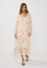 [Color: Natural/Dusty Rose] A front facing image of a brunette model wearing a pink floral chiffon midi dress with a flowy silhouette, long sleeves, smocked bib, and tiered skirt. An effortless and romantic floral dress  for the spring season. 