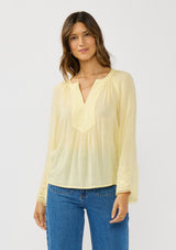 [Color: Yellow] A front facing image of a brunette model wearing a yellow blouse with tonal embroidery, long bell sleeves, and  split v-neckline. A lightweight and sheer top for the spring season. 