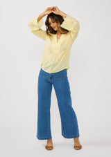 [Color: Yellow] A front facing image of a brunette model wearing a yellow blouse with tonal embroidery, long bell sleeves, and  split v-neckline. A lightweight and sheer top for the spring season. 