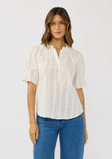 [Color: White] A front facing image of a brunette model wearing a white button up puff sleeve top with a jacquard stripe and  metallic thread details. 
