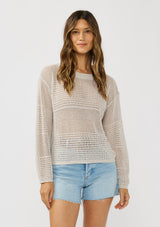 [Color: Stone] A front facing image of a brunette model wearing a grey knit top with silver metallic thread, a round neck, long sleeves, and open knit details. 