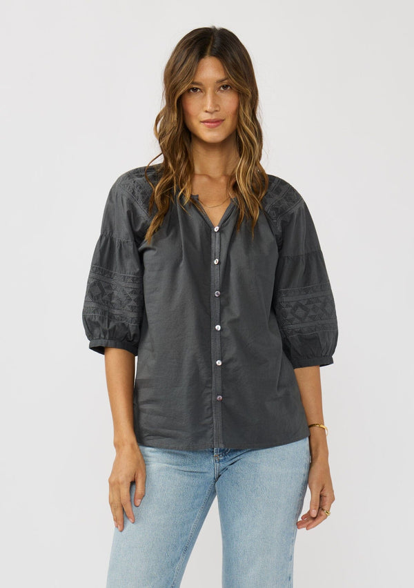 [Color: Grey] A front facing image of a brunette model wearing bohemian grey embroidered blouse with 3/4 length sleeves and a decorative button front. 