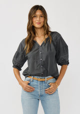 [Color: Grey] A front facing image of a brunette model wearing bohemian grey embroidered blouse with 3/4 length sleeves and a decorative button front. 