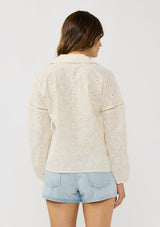 [Color: Tea Dye] A back facing image of a brunette model wearing a tonal embroidered blouse with a collared v-neckline and long sleeves with elastic cuffs. A breezy cotton blouse for casual settings. 