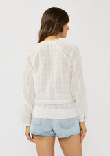 [Color: White] A back facing image of a brunette model wearing a plaid sheer blouse with lace and pintuck details. Featuring a split v-neckline, dainty tie neck detail, and long sleeves. 