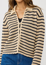 [Color: Tan/Navy] A detail image of a brunette model wearing a tan and navy striped sweater with open knit details, collar, and button front.