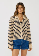 [Color: Tan/Navy] A front facing image of a brunette model wearing a tan and navy striped sweater with open knit details, collar, and button front.