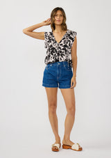 [Color: Vanilla/Black] A front facing image of a brunette model wearing an abstract floral print top with cap sleeves and a split v-neckline with ties. 