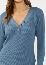 [Color: Heather Ocean] A detail image of a brunette model wearing a blue waffle knit sweater top with a v neckline and a button front detail. 