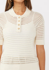 [Color: Vanilla] A detail image of a brunette model wearing an off white cotton open knit top with short sleeves, ribbed trim, and a button front Henley placket.