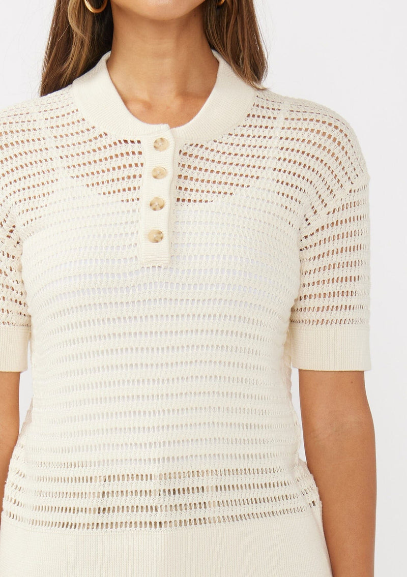 [Color: Vanilla] A detail image of a brunette model wearing an off white cotton open knit top with short sleeves, ribbed trim, and a button front Henley placket.