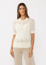 [Color: Vanilla] A front facing image of a brunette model wearing an off white cotton open knit top with short sleeves, ribbed trim, and a button front Henley placket.