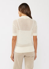 [Color: Vanilla] A back facing image of a brunette model wearing an off white cotton open knit top with short sleeves, ribbed trim, and a button front Henley placket.
