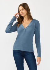 [Color: Heather Ocean] A front facing image of a brunette model wearing a blue waffle knit sweater top with a v neckline and a button front detail. 
