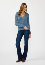 [Color: Heather Ocean] A front facing image of a brunette model wearing a blue waffle knit sweater top with a v neckline and a button front detail. 