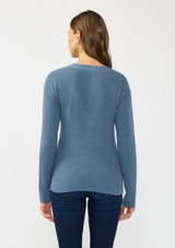 [Color: Heather Ocean] A back facing image of a brunette model wearing a blue waffle knit sweater top with a v neckline and a button front detail. 