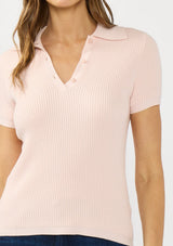 [Color: Light Pink] A detail image of a brunette model wearing a light pink waffle knit polo top with a collared neck and button front. 