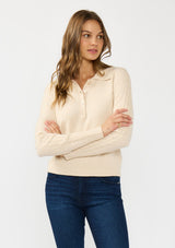 [Color: Stone] A front facing image of a brunette model wearing a beige sweater  polo with a button front, collared neck, and a cable knit detail on the sleeves. 