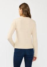 [Color: Stone] A back facing image of a brunette model wearing a beige sweater  polo with a button front, collared neck, and a cable knit detail on the sleeves. 