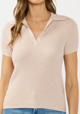 [Color: Heather Pearl] A detail image of a brunette model wearing a light taupe waffle knit polo top with a collared neck and button front. 