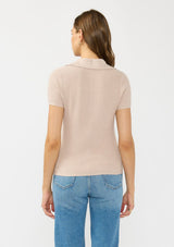 [Color: Heather Pearl] A back facing image of a brunette model wearing a light taupe waffle knit polo top with a collared neck and button front. 