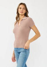 [Color: Rose Dust] A side facing image of a brunette model wearing  a waffle knit polo top with a collared neck and button front. 