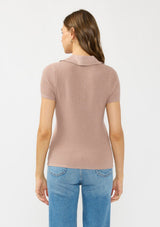 [Color: Rose Dust] A back facing image of a brunette model wearing  a waffle knit polo top with a collared neck and button front. 
