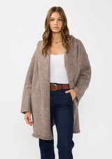 [Color: Heather Woodrose] A front facing image of a brunette model wearing a cozy wool blend coatigan with an oversized fit, hoodie, and side pockets. 