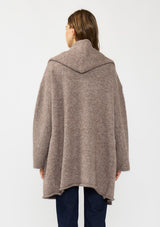 [Color: Heather Woodrose] A back facing image of a brunette model wearing a cozy wool blend coatigan with an oversized fit, hoodie, and side pockets. 