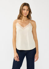 [Color: Vanilla] A front facing image of a brunette model wearing a lace trimmed camisole with a v neckline and adjustable spaghetti straps. 